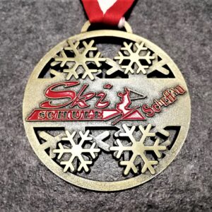 medaglia personalizzata ski schule scheffau in metallo a rilievo 2D con smalto traforata finitura bronzo antico con nastro rossobiancorosso