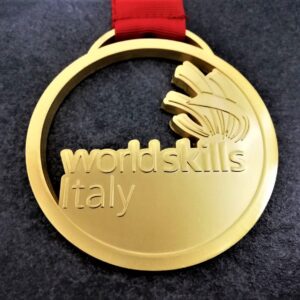 medaglia personalizzata world skills italy in metallo a rilievo 2D traforata finitura oro satinato con nastro personalizzato in serigrafia
