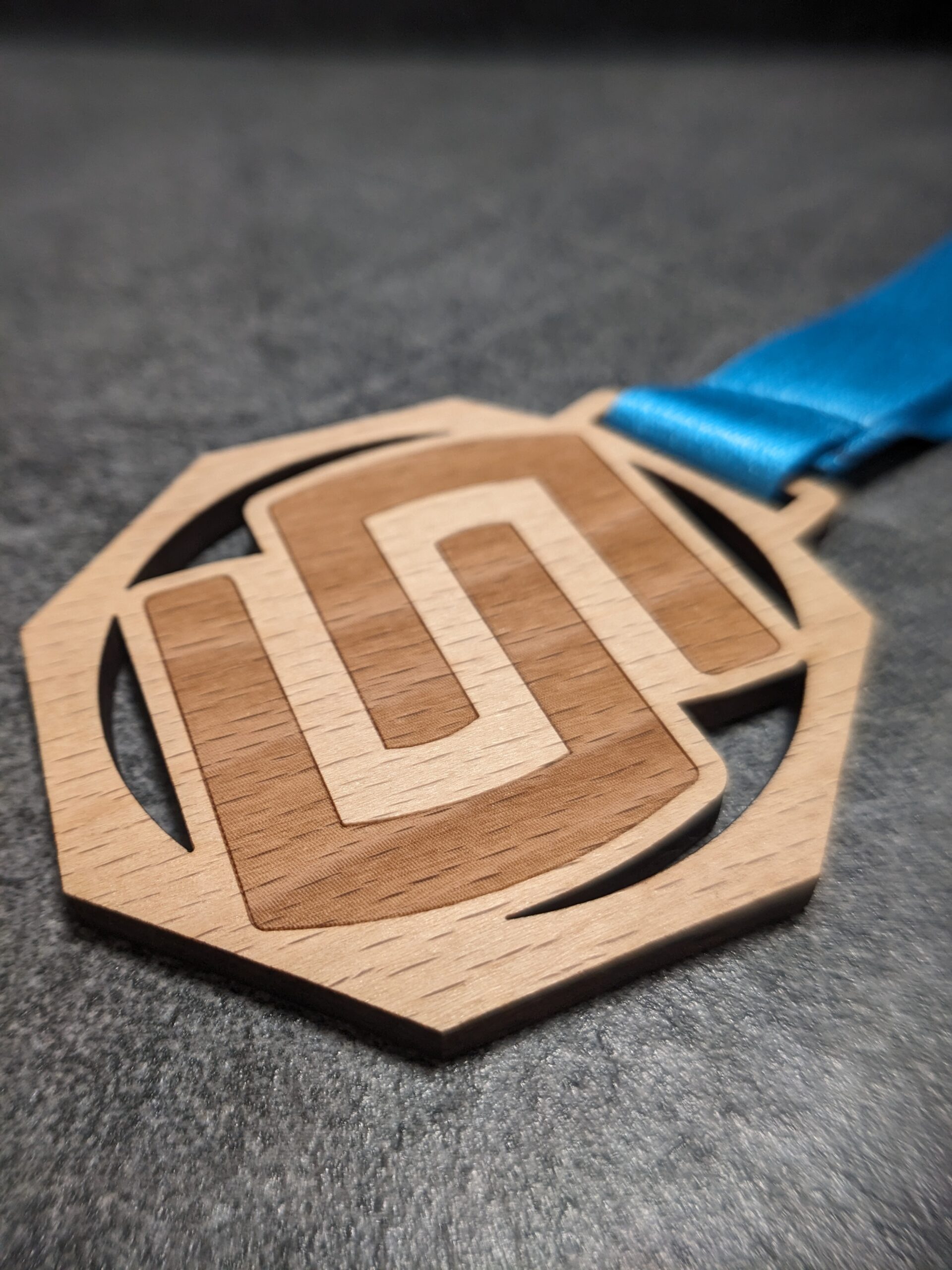 custom stelvio marathon octagonal medal in natural laser-cut and engraved wood with personalized sublimation ribbon side view custom stelvio marathon octagonal medal in natural laser-cut and engraved wood with personalized sublimation ribbon side view